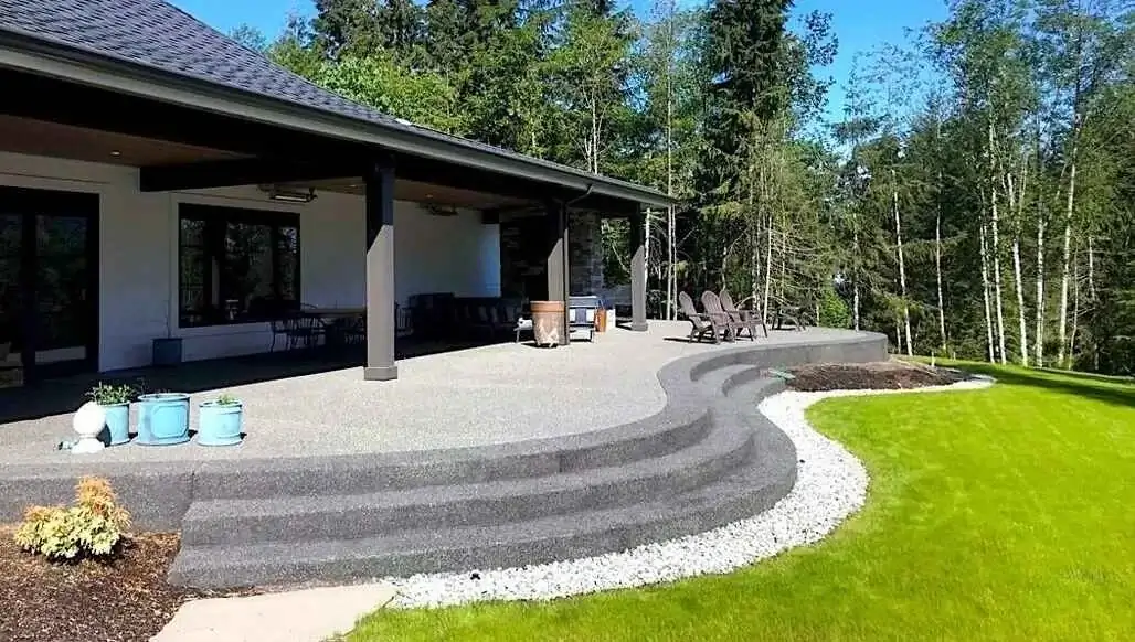 Exposed aggregate concrete patio with outdoor kitchen in Bellevue, WA showcasing natural stone beauty