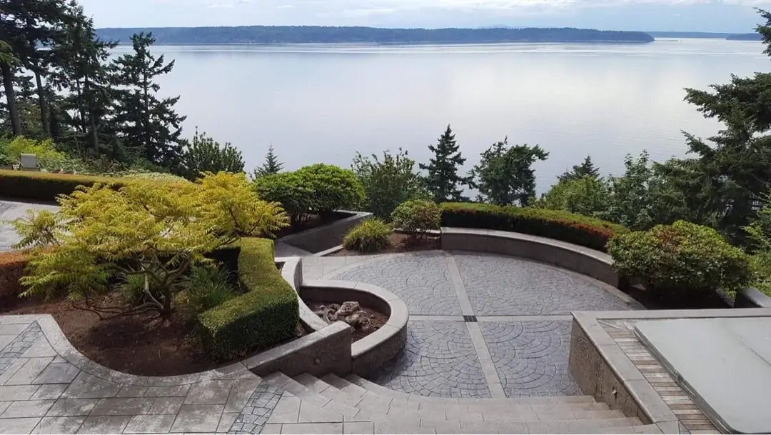 Waterfront view from the stamped concrete patio in Burien, WA, featuring a curved seat wall and landscaping.