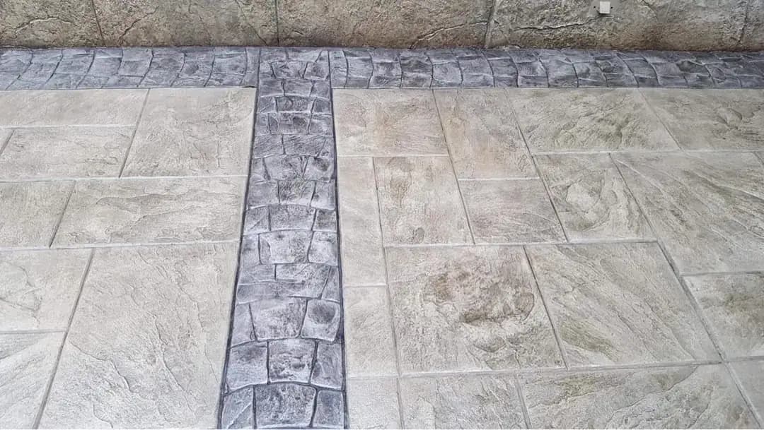 Close-up of the stamped concrete surface showing a large tile pattern next to a dark cobblestone border.
