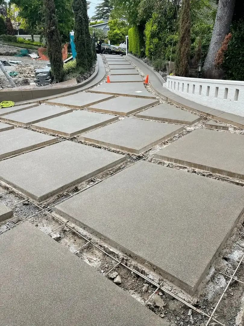 View of the newly poured concrete pads with exposed rebar in the gaps, awaiting the cobblestone installation.