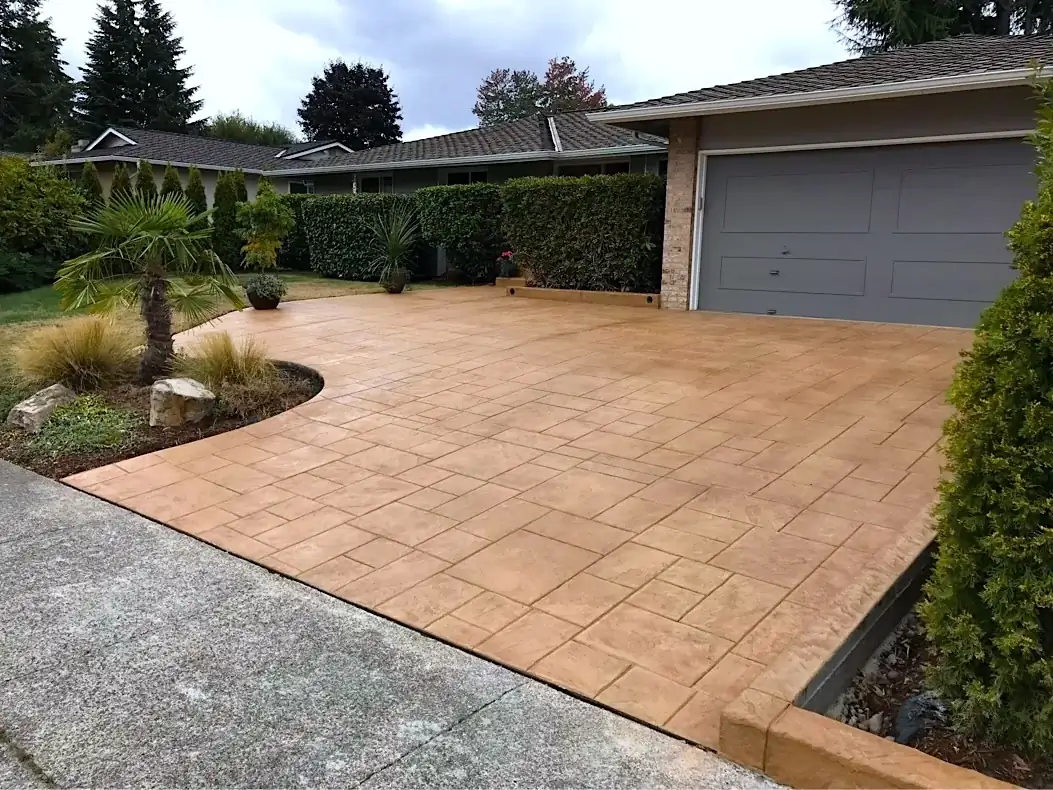 Wide angle of a new Ashlar slate stamped concrete driveway and garage apron in Tacoma, showing the warm tan color.