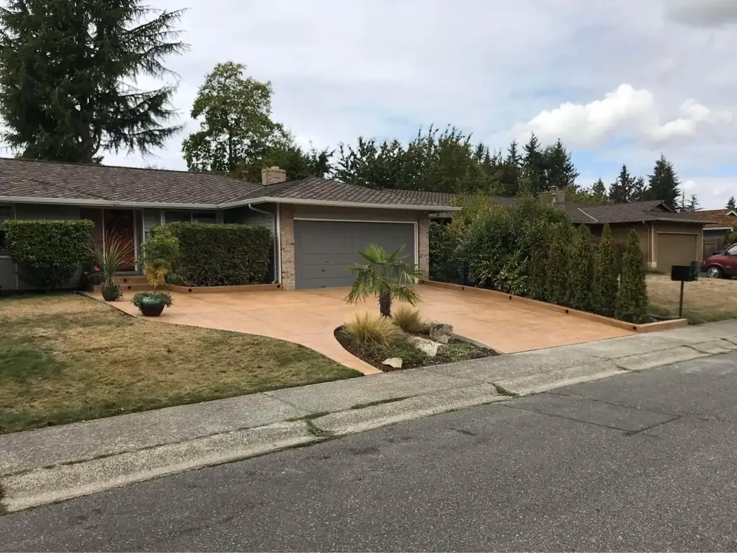 Street view of a residential stamped concrete driveway in Tacoma with a graceful curve around a landscaped island.