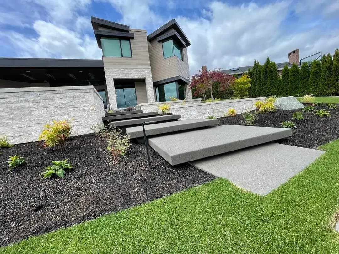 Floating exposed aggregate concrete steps leading up to a modern home in Puyallup with integrated landscape lighting.