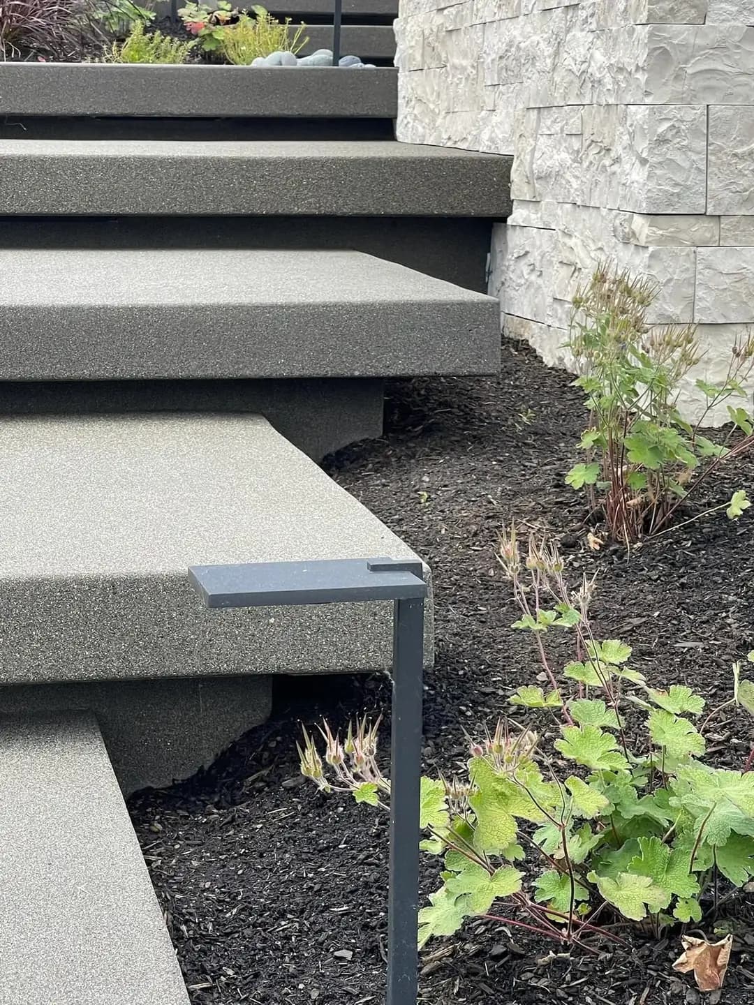 Close-up of the fine texture on exposed aggregate floating steps next to a modern, low-profile light fixture.