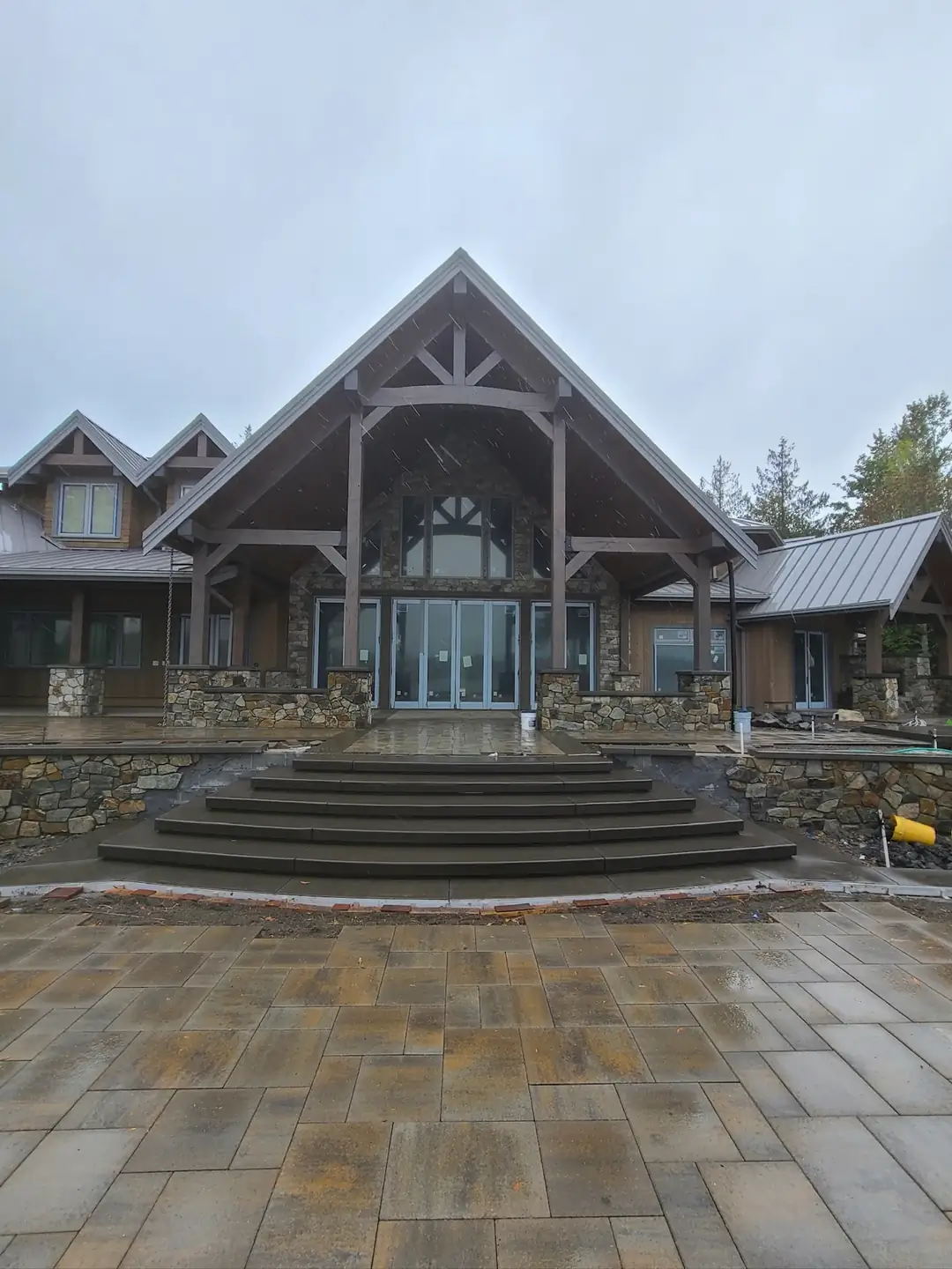 A complete view of the newly installed concrete steps set against a large paver patio and rustic home facade.