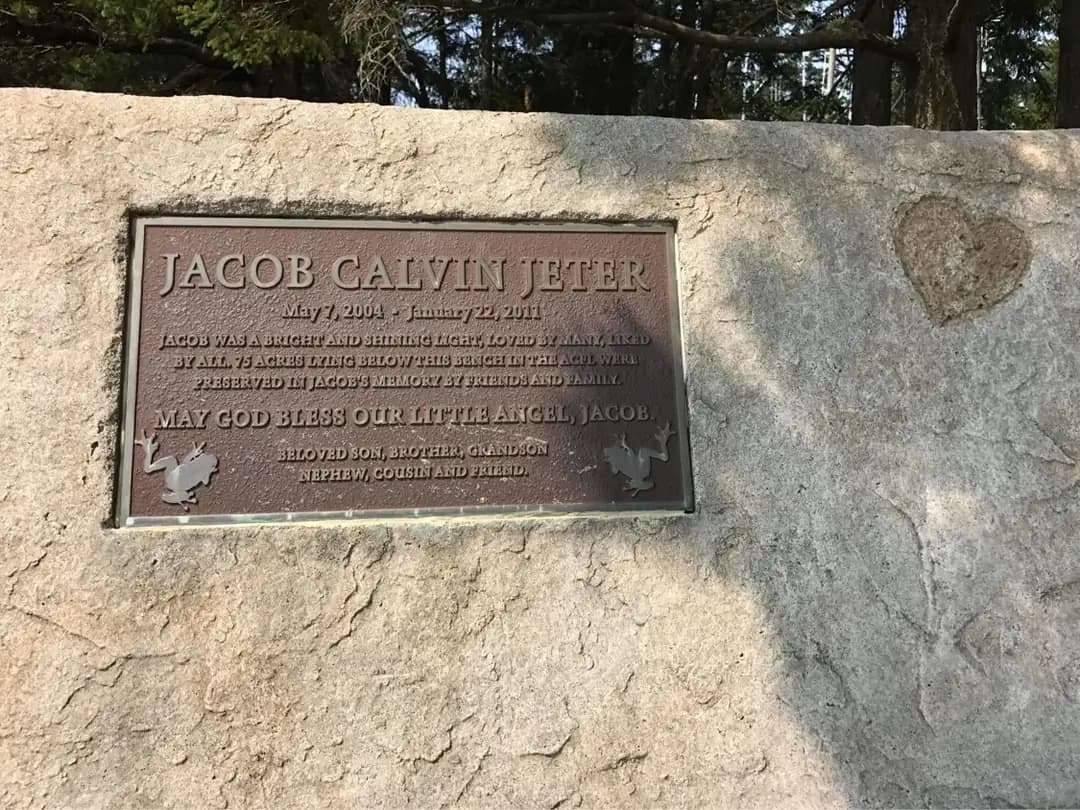 Close-up of the recessed bronze memorial plaque on the custom concrete bench in Tacoma, showing the stone texture.