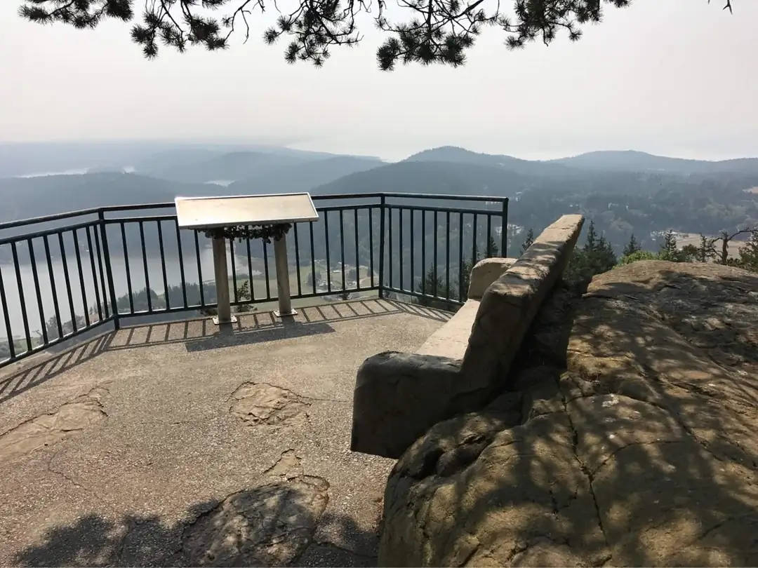 View from behind the concrete bench looking out over the scenic landscape and metal safety railing.