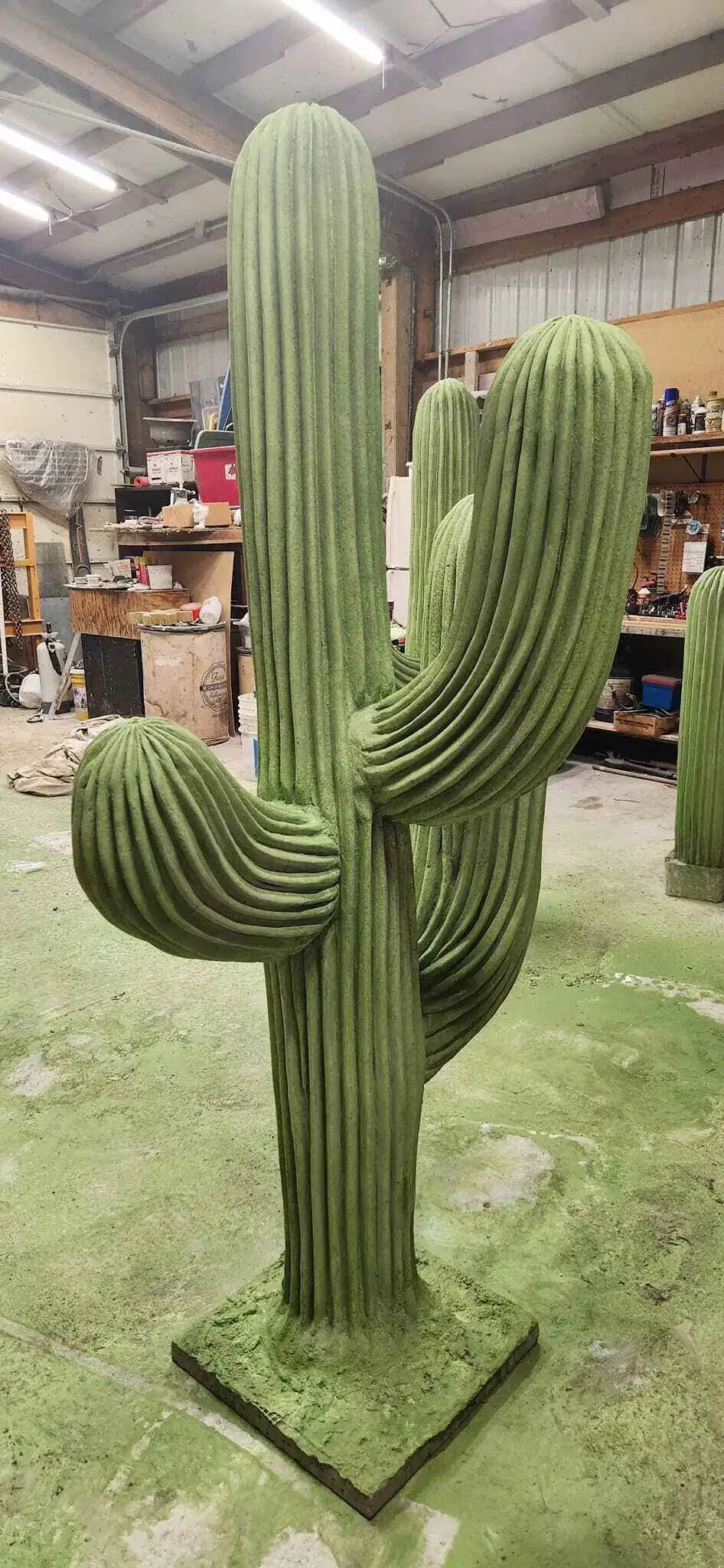 A close-up profile of a concrete cactus sculpture in a workshop, showing the detailed ribbed texture.