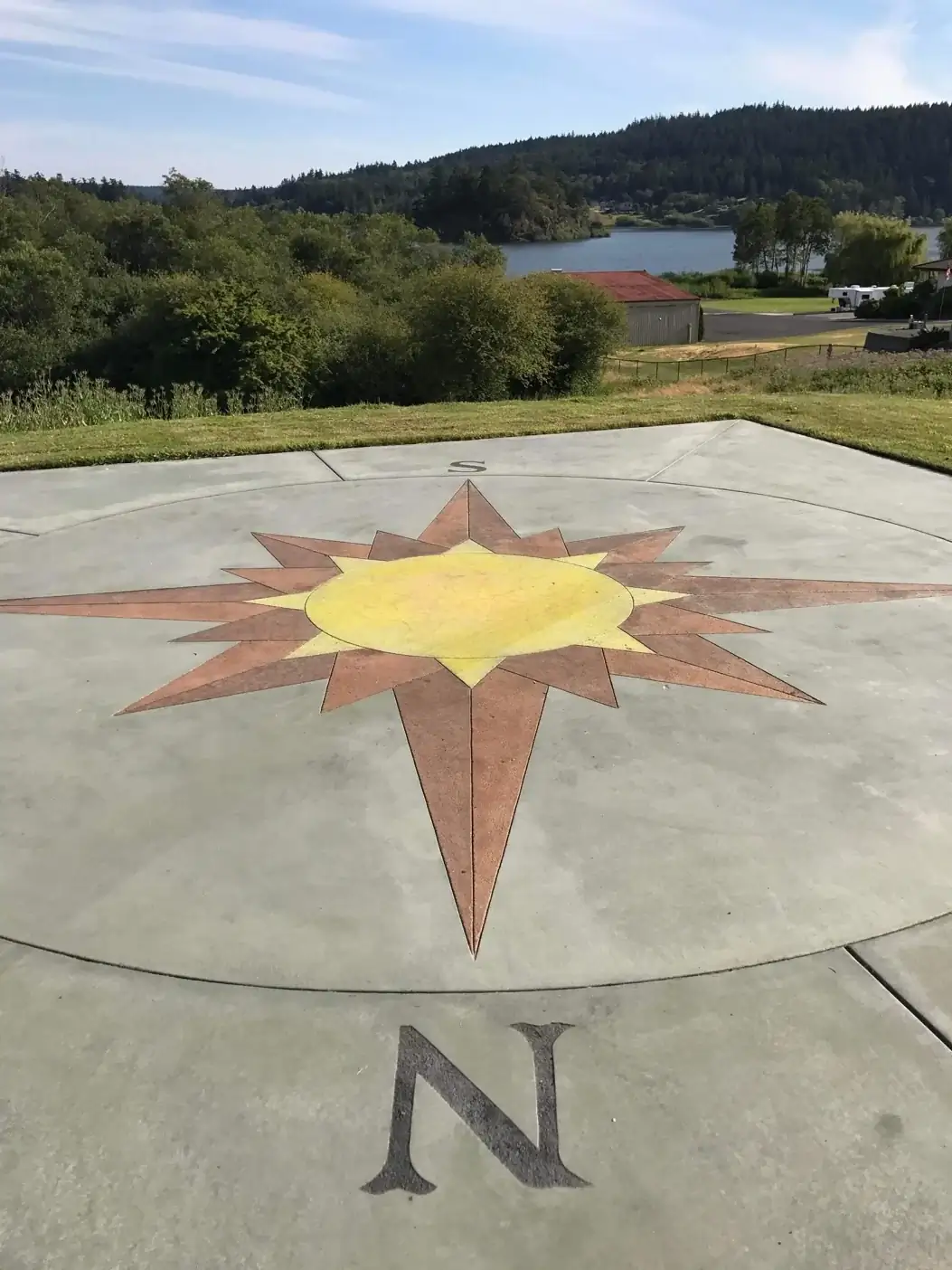 Waterfront view behind a large concrete patio in Bellevue with a central yellow and brown star medallion.