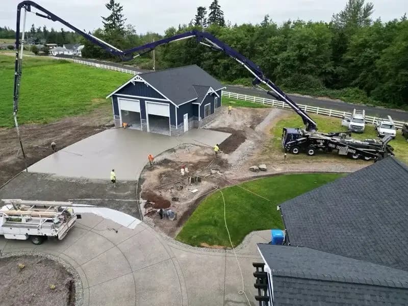 Aerial view of a concrete pump truck pouring a new exposed aggregate driveway apron in Buckley, WA for a detached garage.