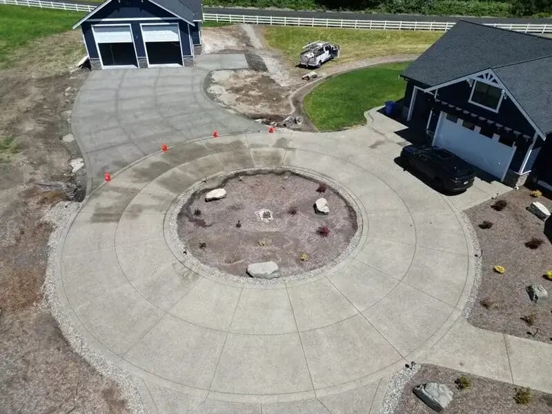 High-angle view of a circular driveway feature with radial and concentric saw-cut joints for a decorative effect.