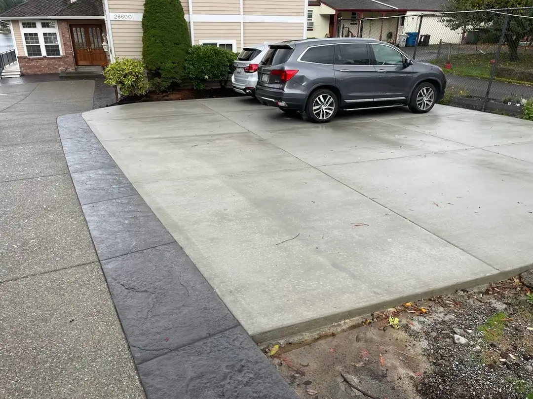 Broom-finished concrete parking pad adjacent to the main exposed aggregate driveway in Kent, WA.
