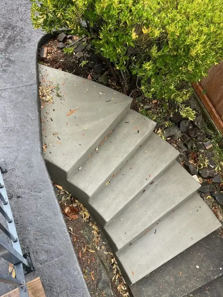 Set of five broomed-finish concrete steps leading down a landscaped slope in Kent, WA.