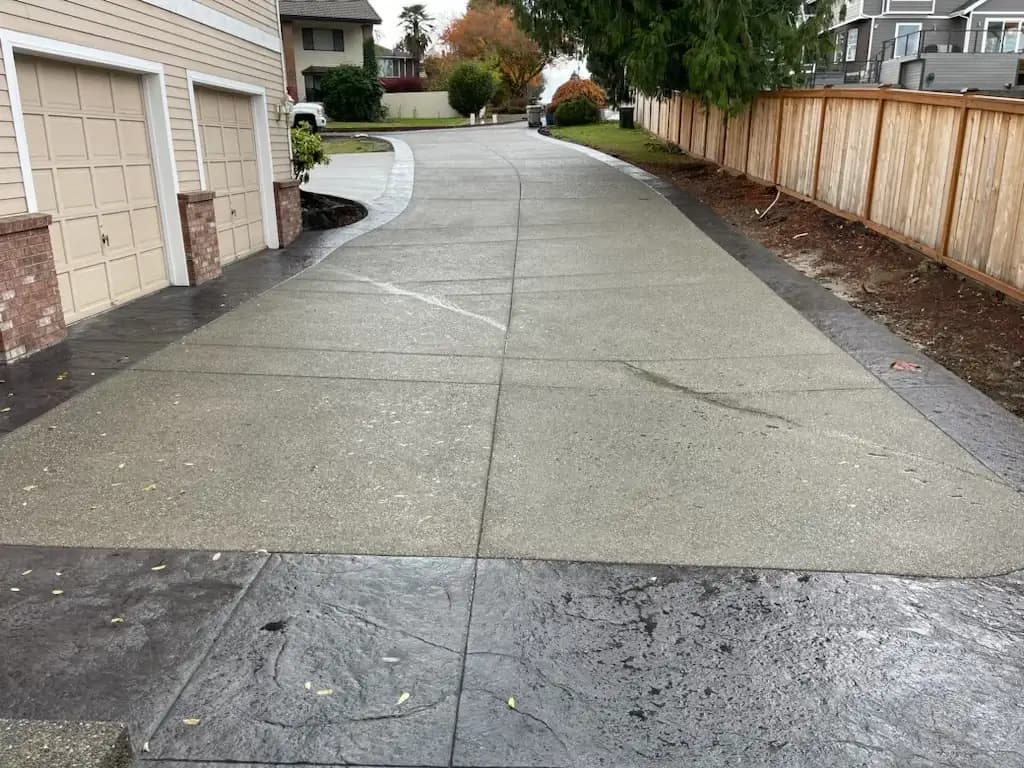 View down the long exposed aggregate driveway, showing the stamped border and saw-cut joints.