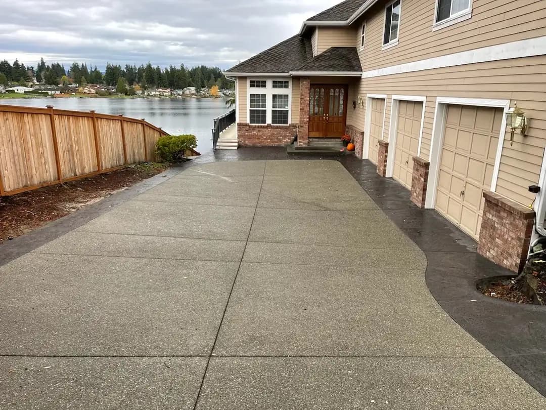 Wide view of the exposed aggregate driveway and turnaround area in front of a three-car garage.