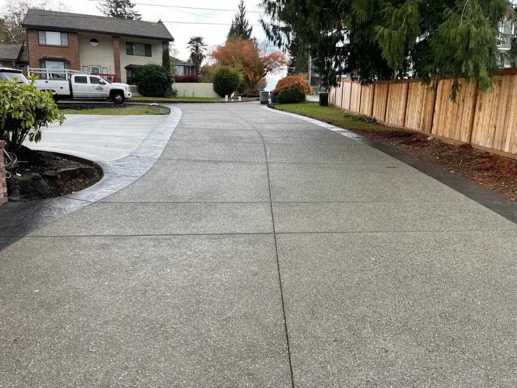 Looking up the sloped exposed aggregate driveway toward the street, framed by a stamped border.