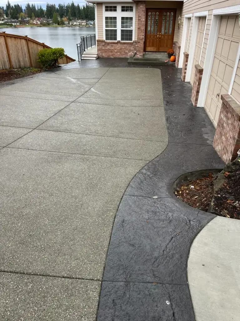 Curved stamped concrete border wrapping around a planter bed next to the exposed aggregate driveway.