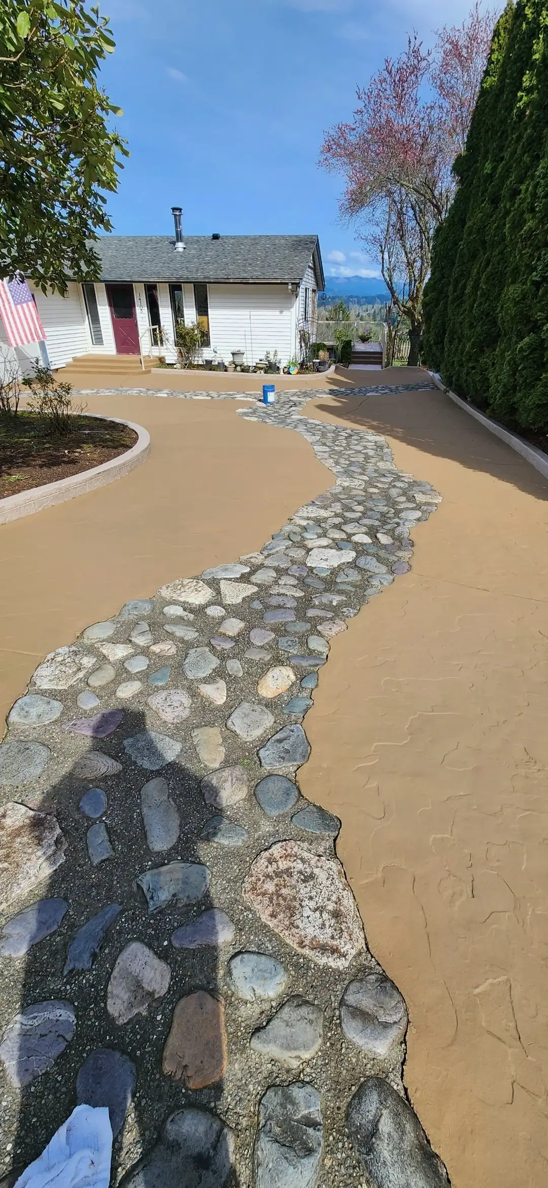 A close-up view of the river stone inlay during the sealing process on a new concrete driveway in Puyallup.