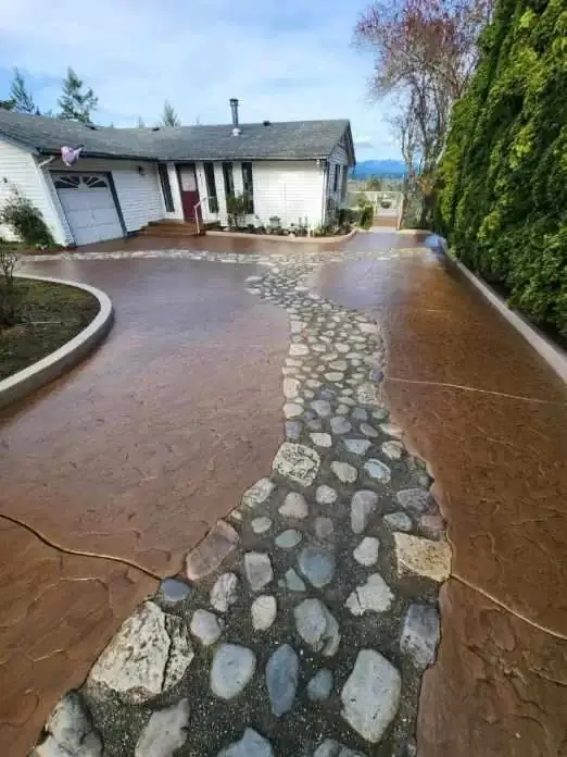 Wide angle of the brown stamped concrete driveway showing its full length from the garage to the street entrance.