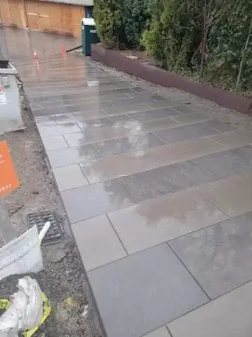 Side angle of a smooth concrete walkway in Yarrow Point, WA, highlighting the saw-cut pattern and Corten steel border.