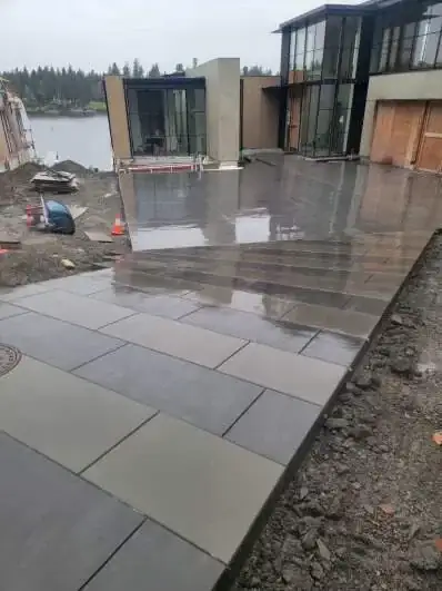 View from the top of the driveway looking down towards a waterfront, showing the large patio area.