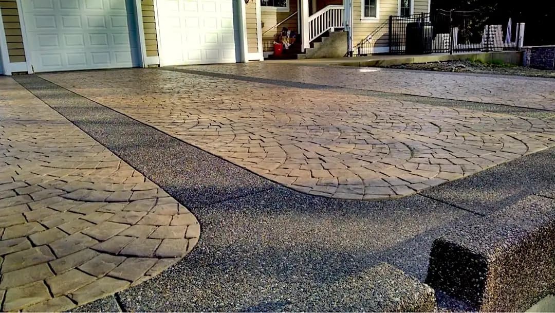 A finished European fan stamped concrete driveway in Bellevue with dark exposed aggregate borders and integrated curbing.