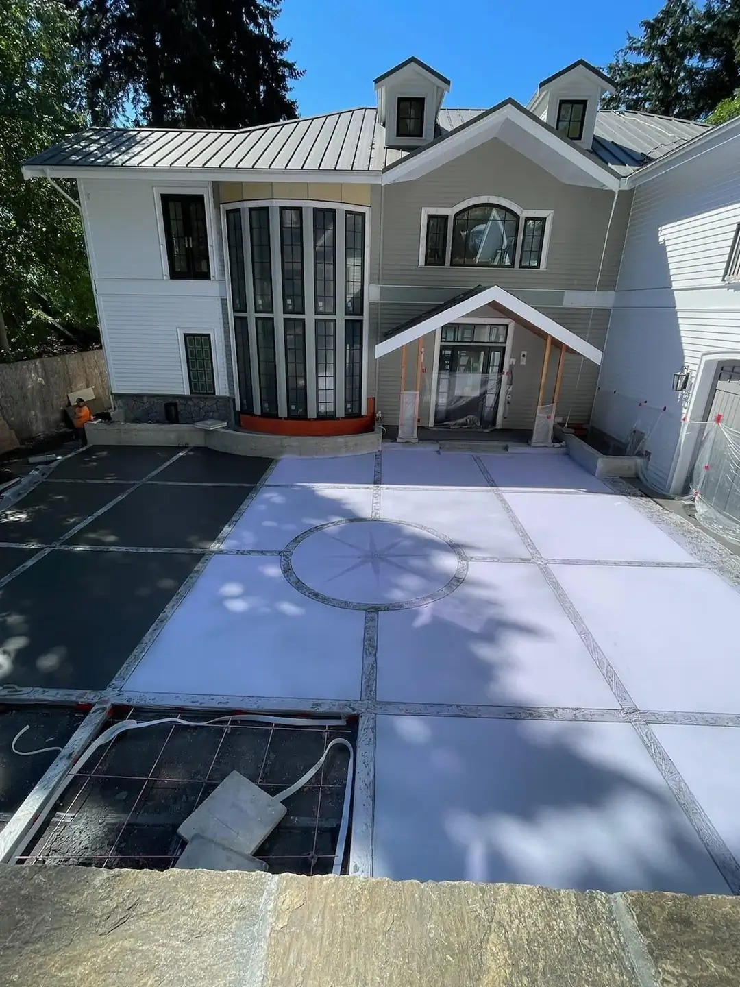 Overhead view of the driveway pour in progress, showing the grid layout and the compass design taking shape.