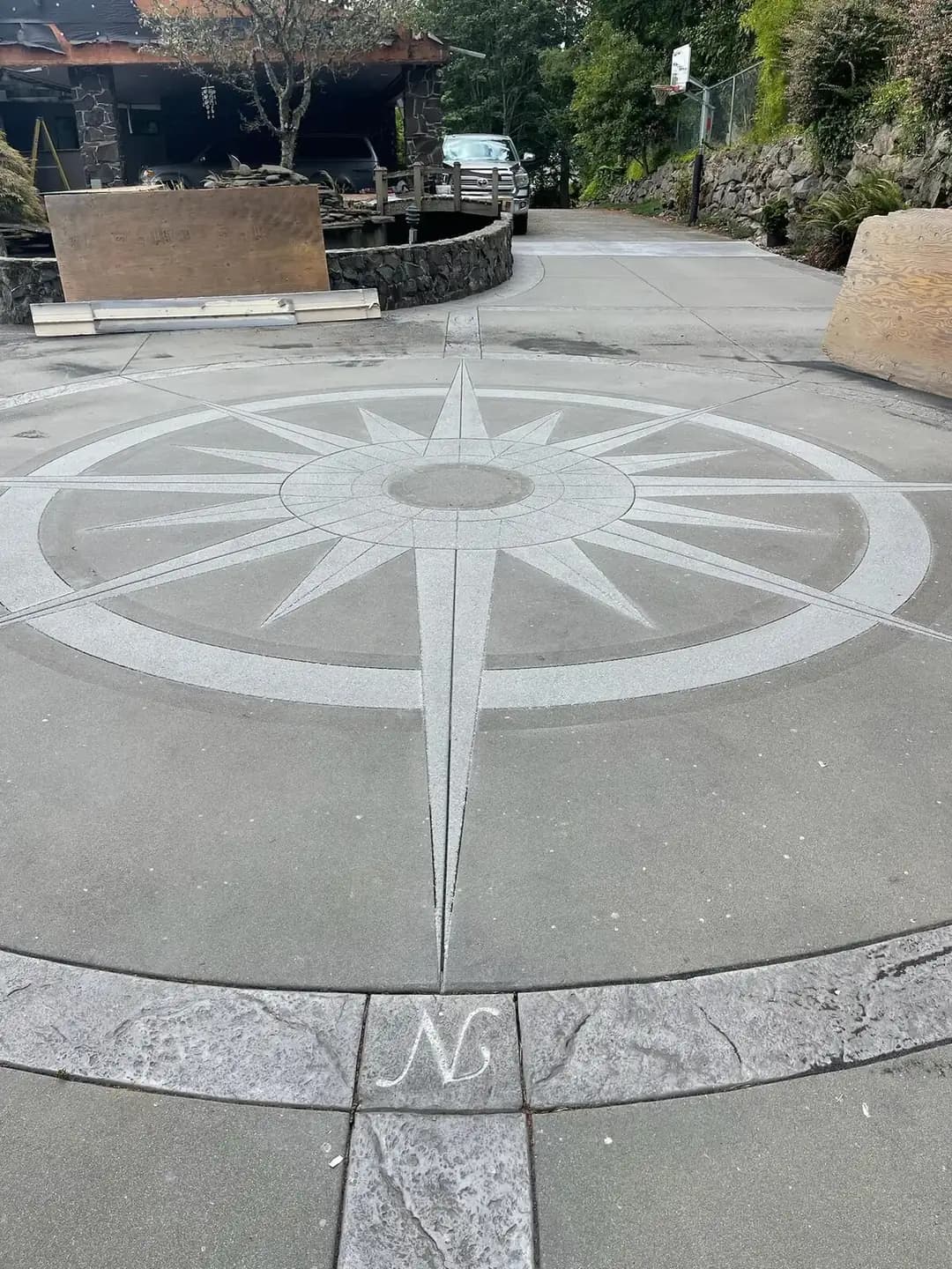 Close-up of a custom compass rose medallion on a new concrete driveway in Puyallup, with a stamped stone border.
