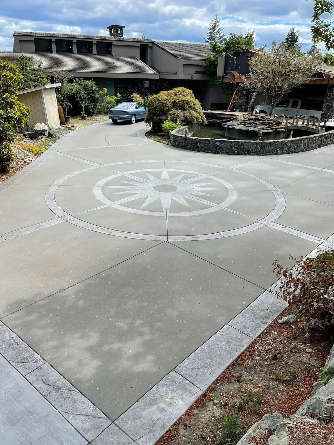 Wide view of a large concrete driveway in Puyallup featuring a central compass design and decorative stamped borders.