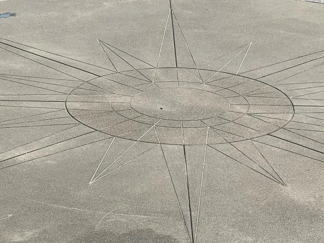 Detailed view of the precise saw-cut lines creating the compass rose design for a custom concrete project in Puyallup.