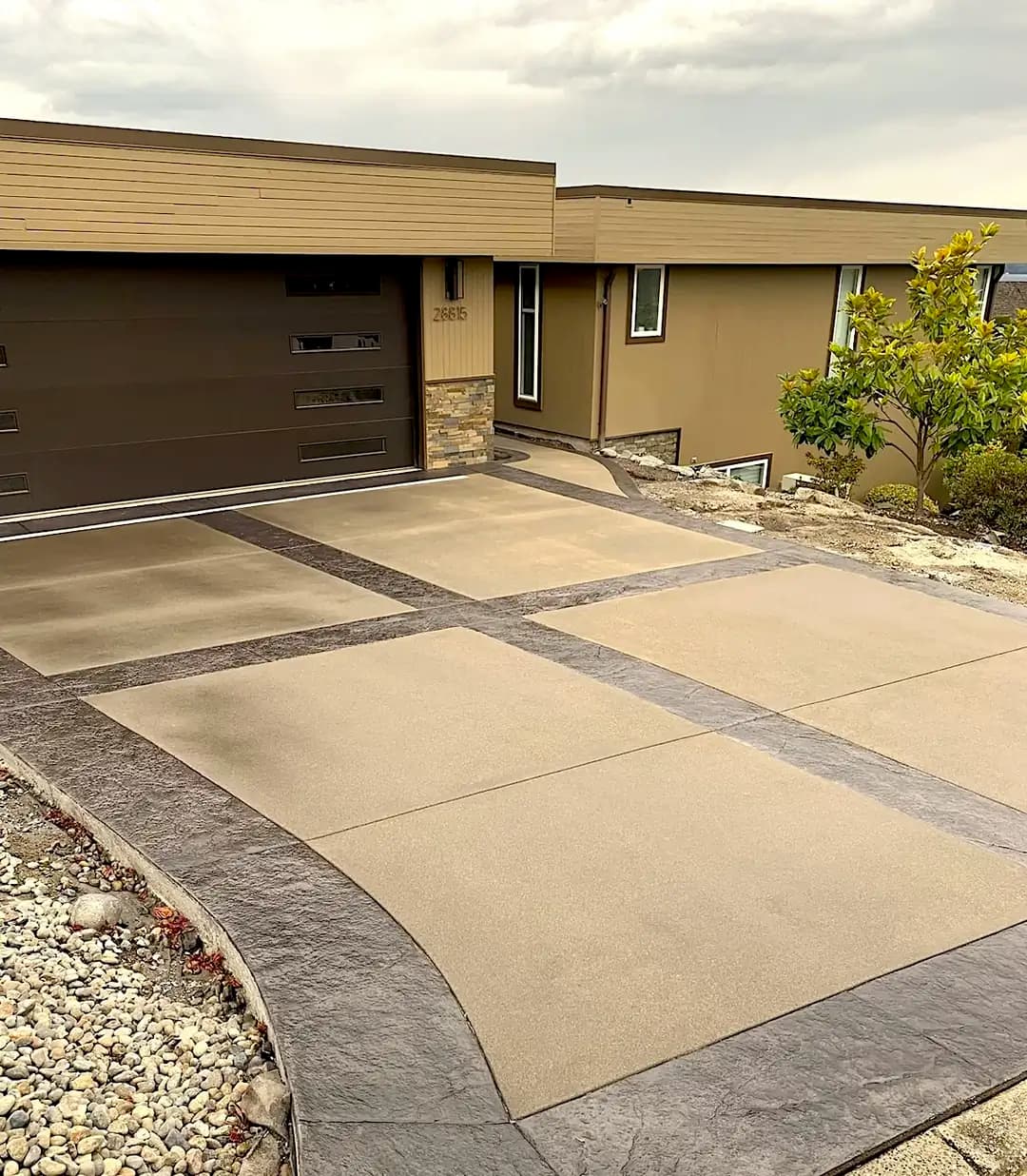 Wide view of a new concrete driveway in Federal Way, WA, featuring a sand finish and dark stamped borders.