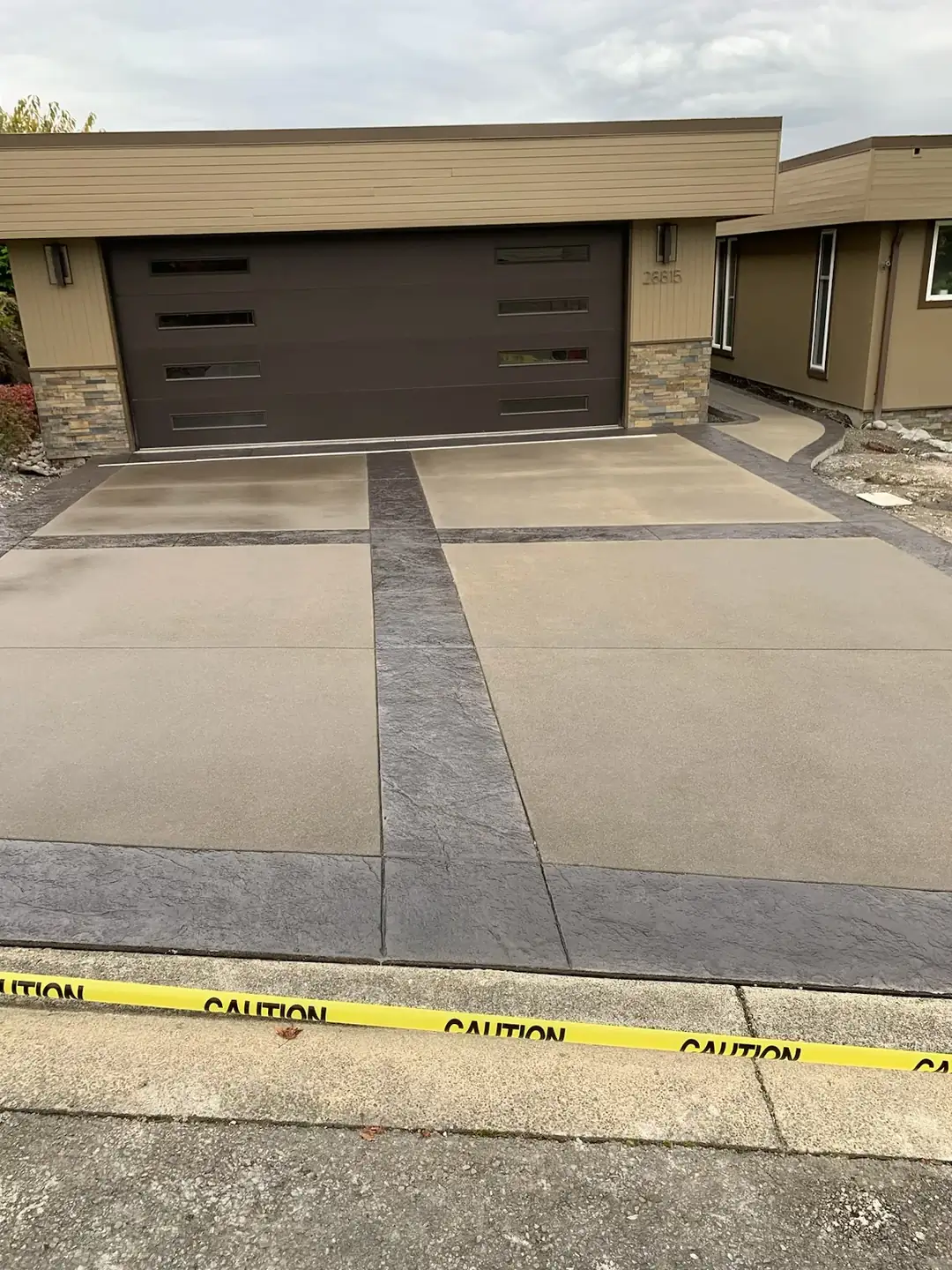 A two-tone concrete driveway and garage apron in Federal Way, WA, with a light sand finish and dark borders.