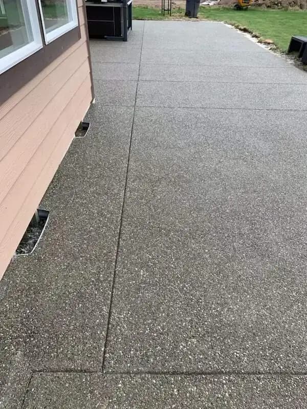 Detailed view of the exposed aggregate surface and control joints along the foundation of a home.