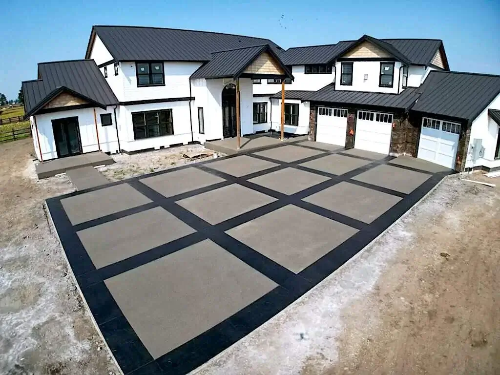Wide angle of a new concrete driveway in Puyallup with a two-tone grid pattern in front of a modern farmhouse.