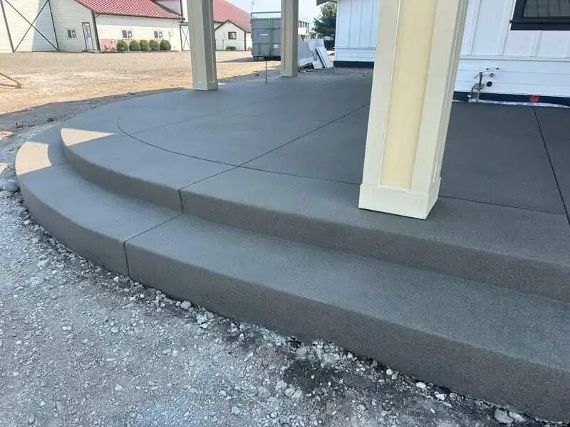 Detail of the curved, two-tier concrete steps with a clean sand finish leading to the back patio.