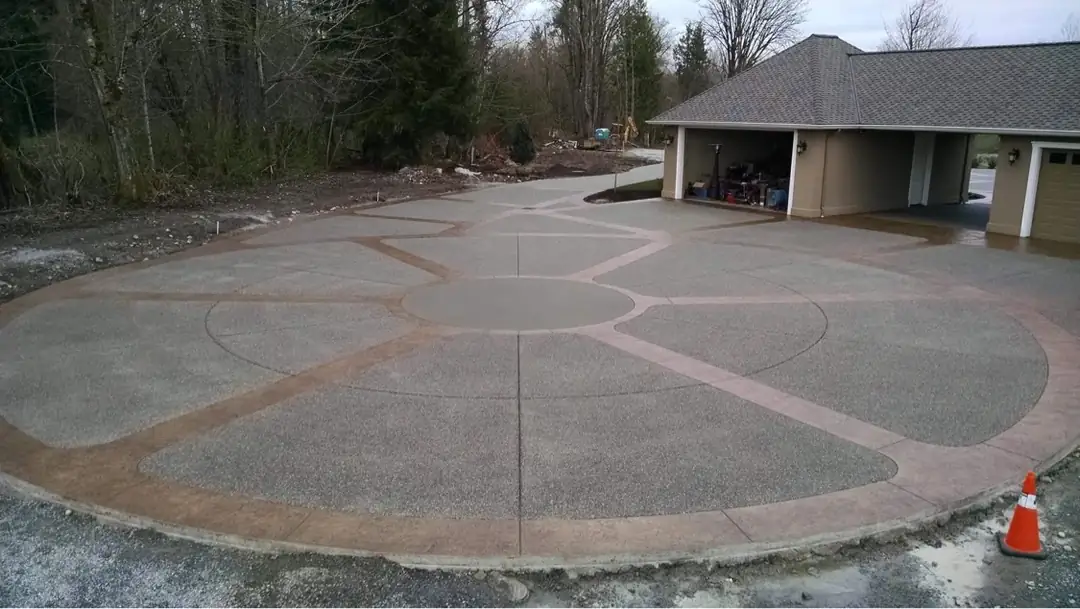 Exposed aggregate driveway with a circular pattern created by colored, stamped concrete borders.