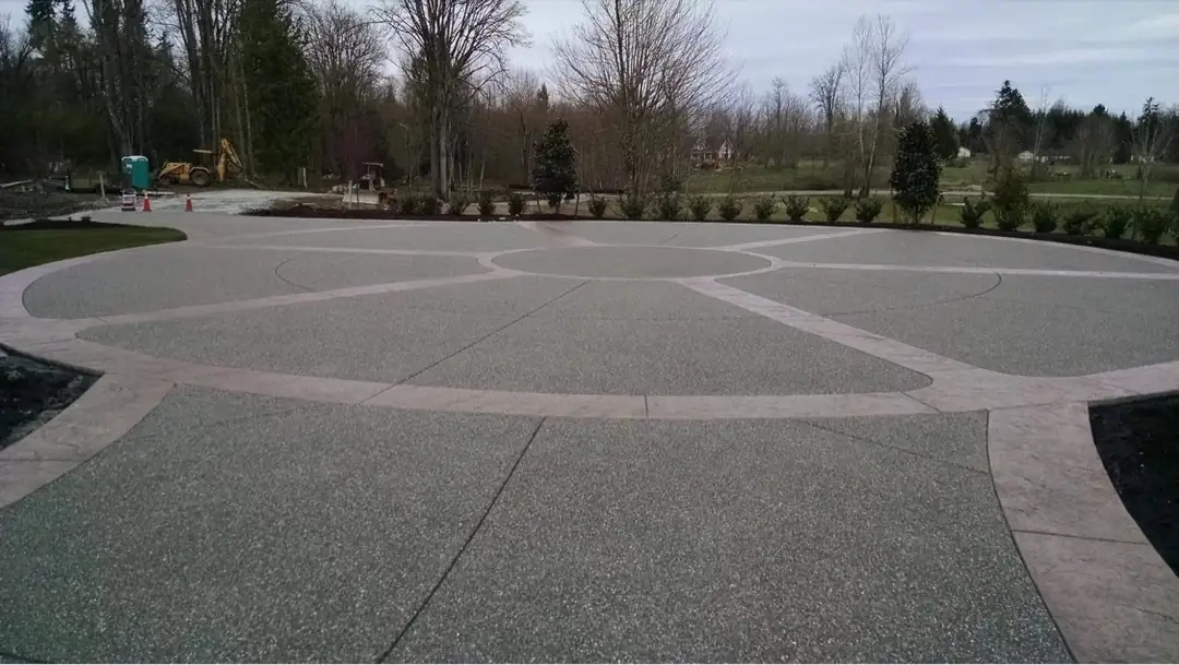 Wide view of the exposed aggregate driveway featuring a large central circle and stamped borders.