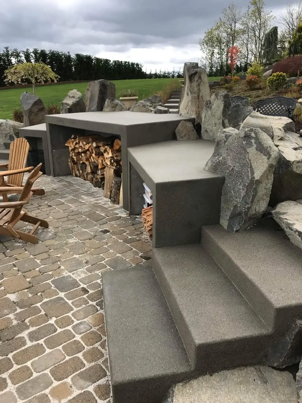 Modern concrete steps with a light aggregate finish leading to a patio with custom seating.