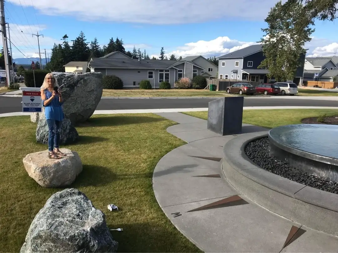 A curved concrete walkway leading towards the central water feature with its distinct compass design.