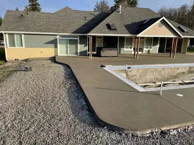 View showing the smoothly curved edge of the sand finish concrete patio as it meets the gravel landscaping.