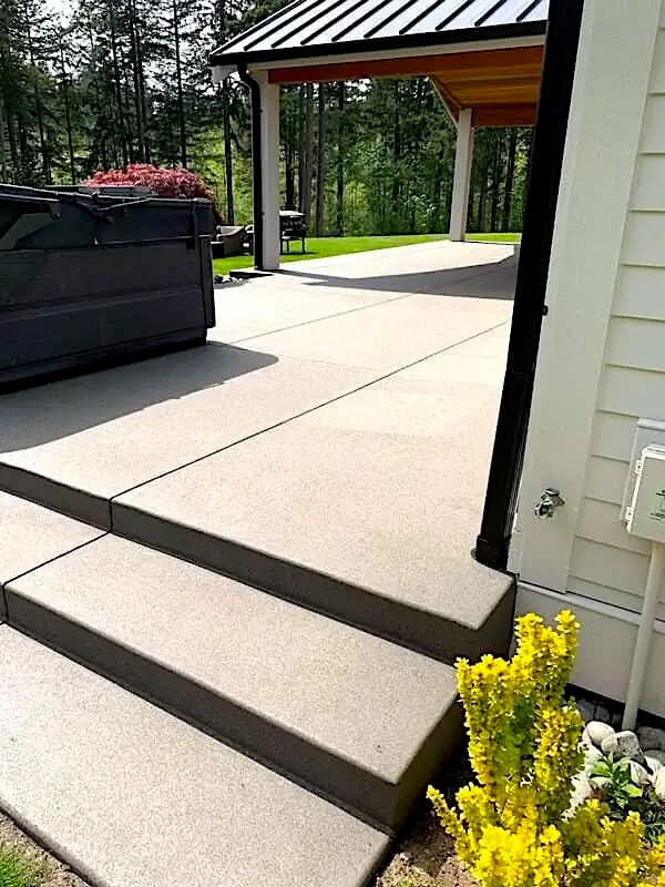 Side view of a multi-level sand finish concrete patio and steps next to a modern home in Auburn, WA.
