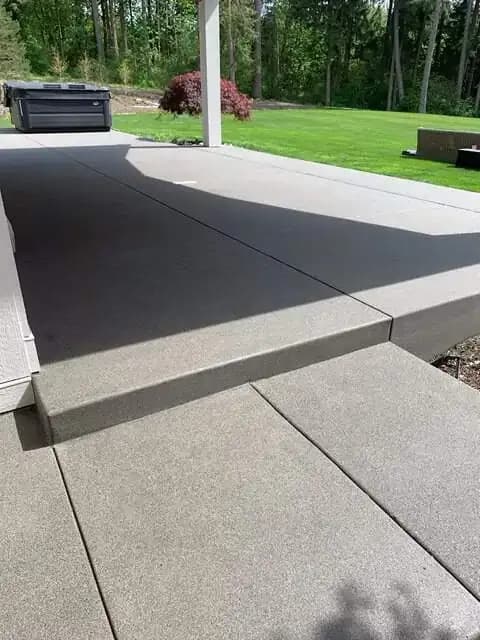 Long view of a spacious sand finish concrete patio with precise saw-cut control joints in Auburn, WA.