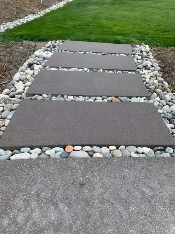 Modern walkway with rectangular concrete pavers and decorative river rock creating a natural path.