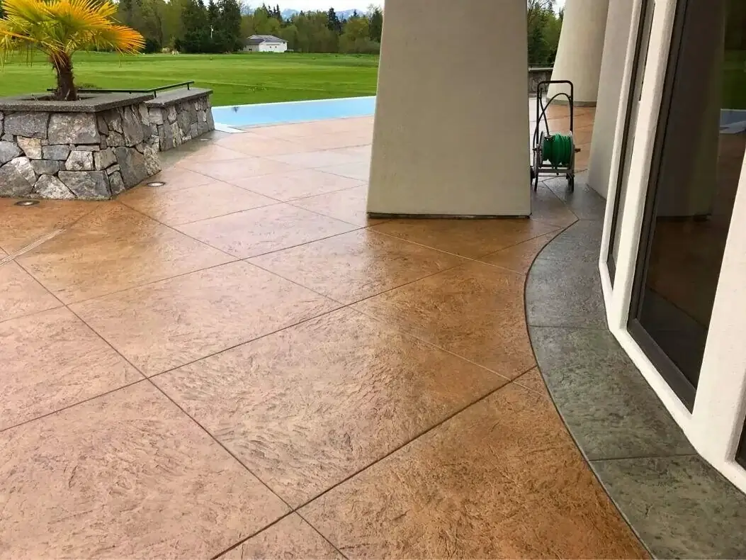 A stamped concrete patio with a dark, smooth border contrasting with the main textured tile pattern.