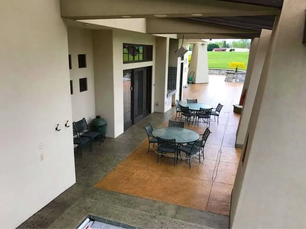 Overhead view of a covered stamped concrete patio with designated areas for outdoor dining and cooking.