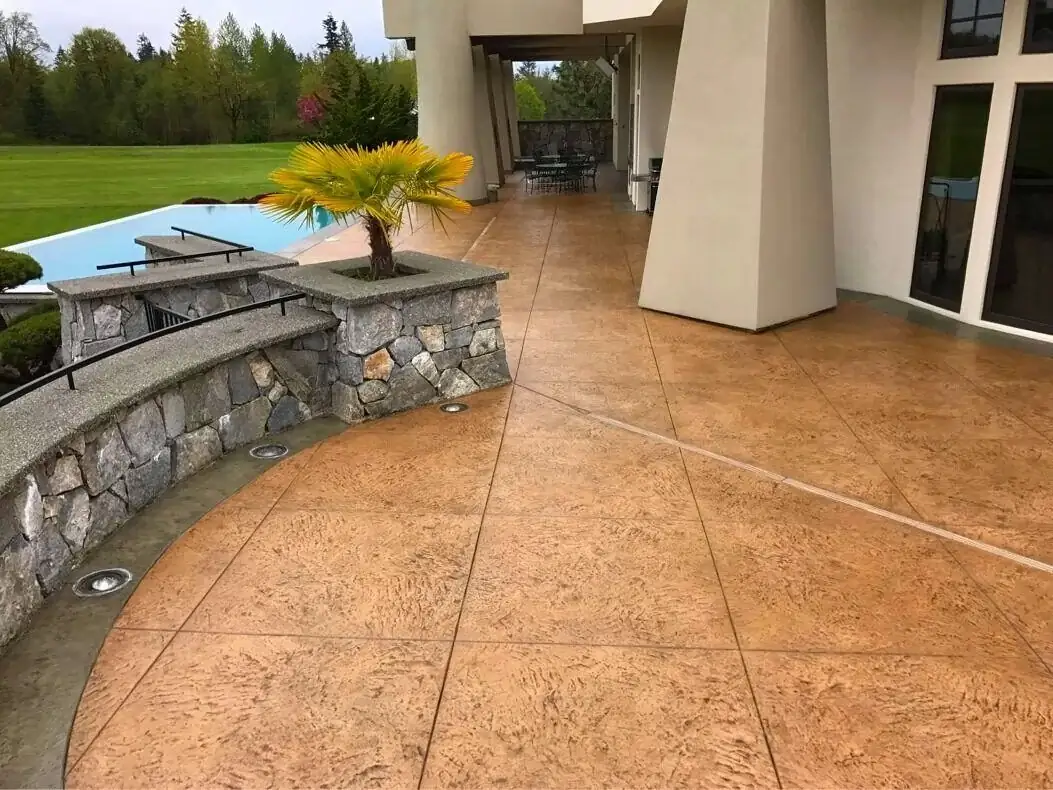 Curved section of a stamped concrete patio featuring a dark border and flush-mounted, in-ground lighting.