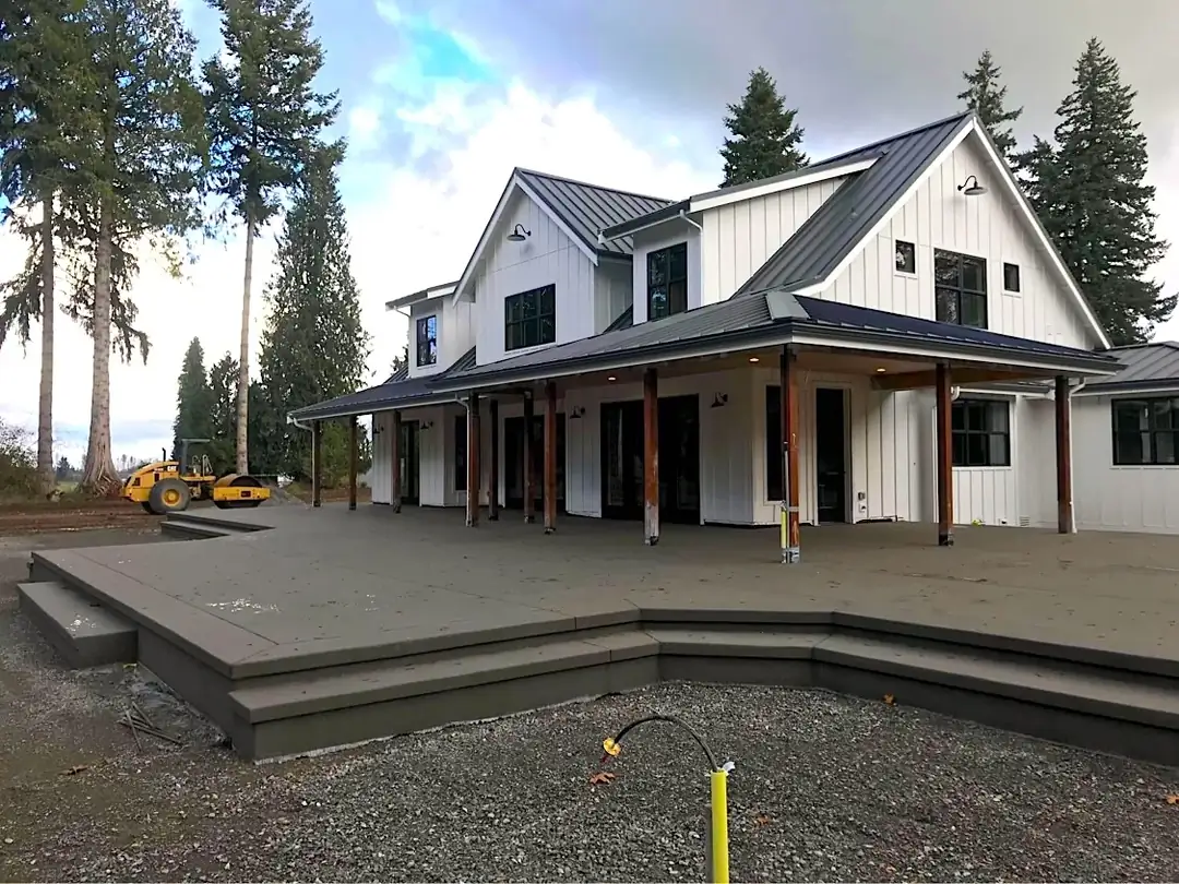 Wide view of a new multi-level sand finish concrete patio with integrated steps in Bellevue, WA, at a modern home.