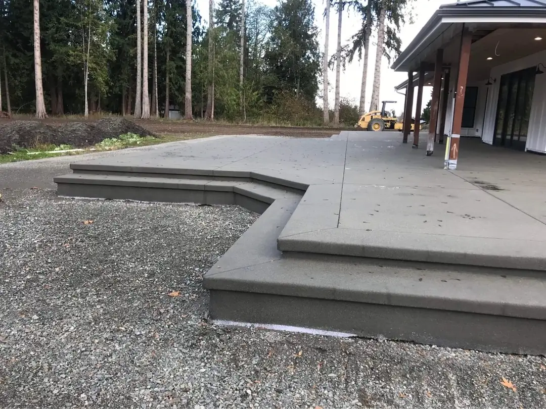Close-up of the corner of a tiered concrete patio in Bellevue, showing the sand finish texture and clean saw cuts.