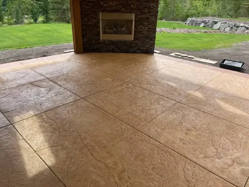 A stamped concrete patio featuring a multi-tone sandstone finish that mimics the look of natural stone.