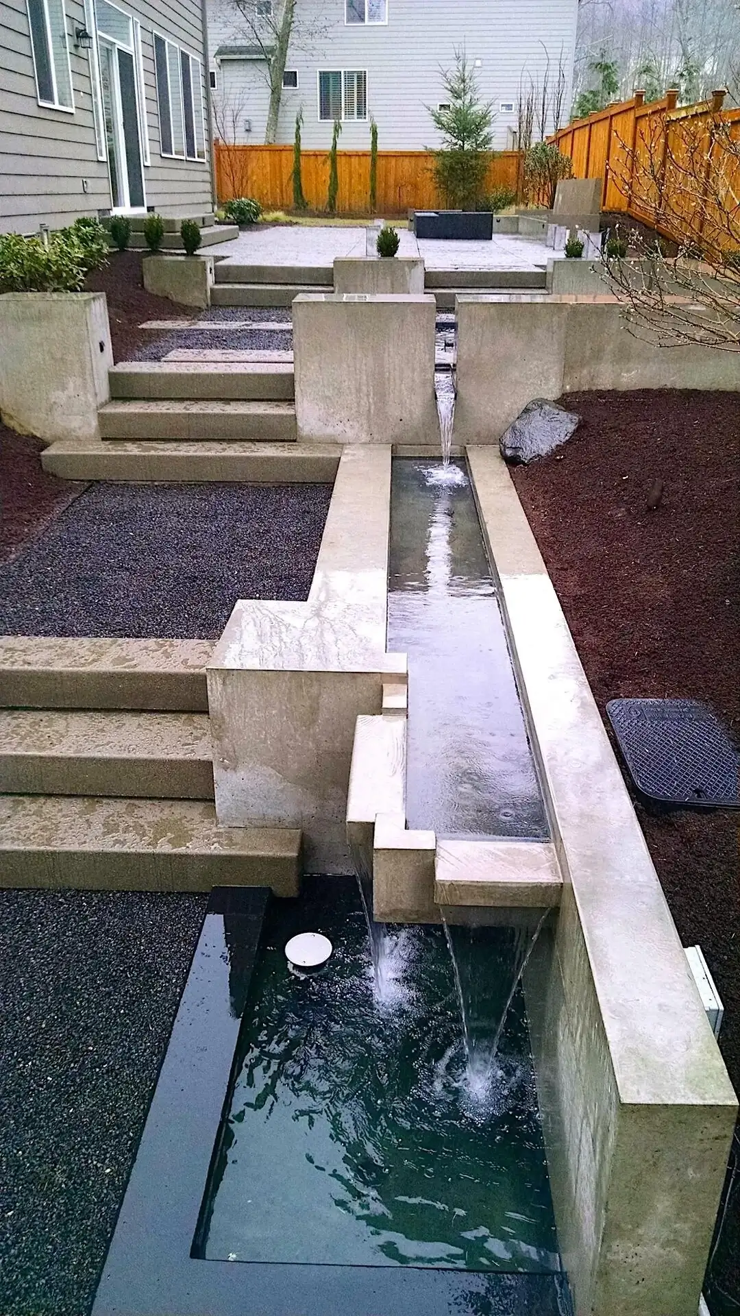 View from above of the cascading concrete water feature and steps in a custom Bellevue residential project.